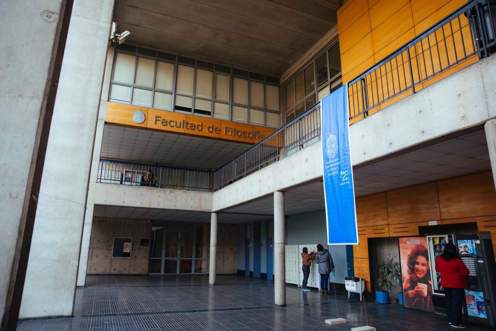 Esquina de edificio de facultad de filosofía destaca un banner de color azul, con el logo de la Universidad mostrando los 130 años