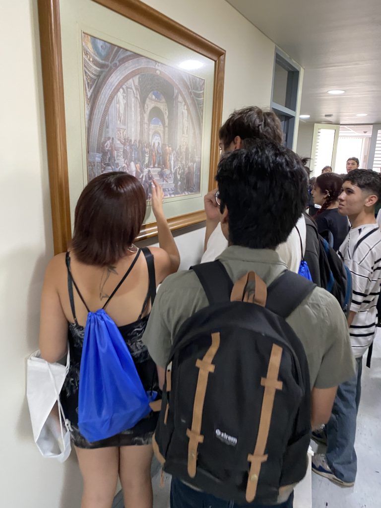 En la imagen aparece un grupo de estudiantes de primer año recorriendo el segundo piso del Instituto y tratan de reconocer a los filósofos que aparecen en un cuadro
